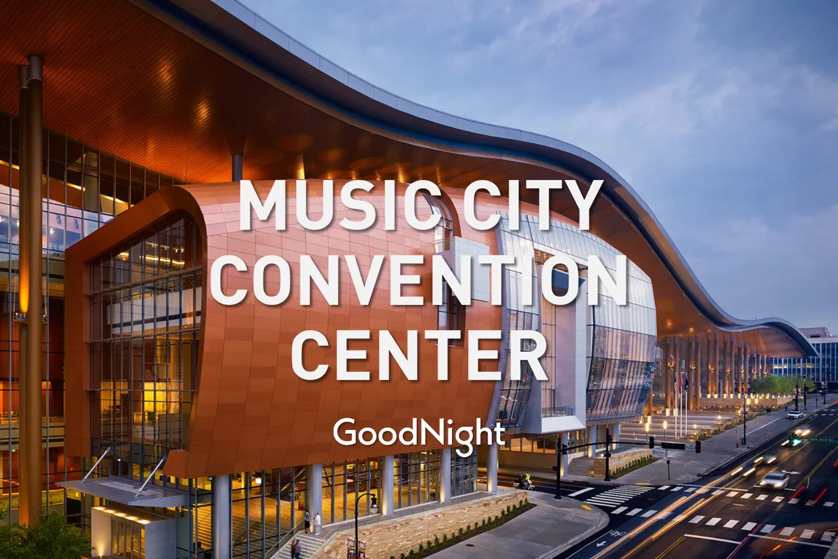The exterior of the Music City Convention Center features dynamic, wave-like modern architecture with large glass windows and a vibrant orange and silver facade. The image captures the venue's bustling atmosphere, hinting at major conferences and social gatherings taking place inside.